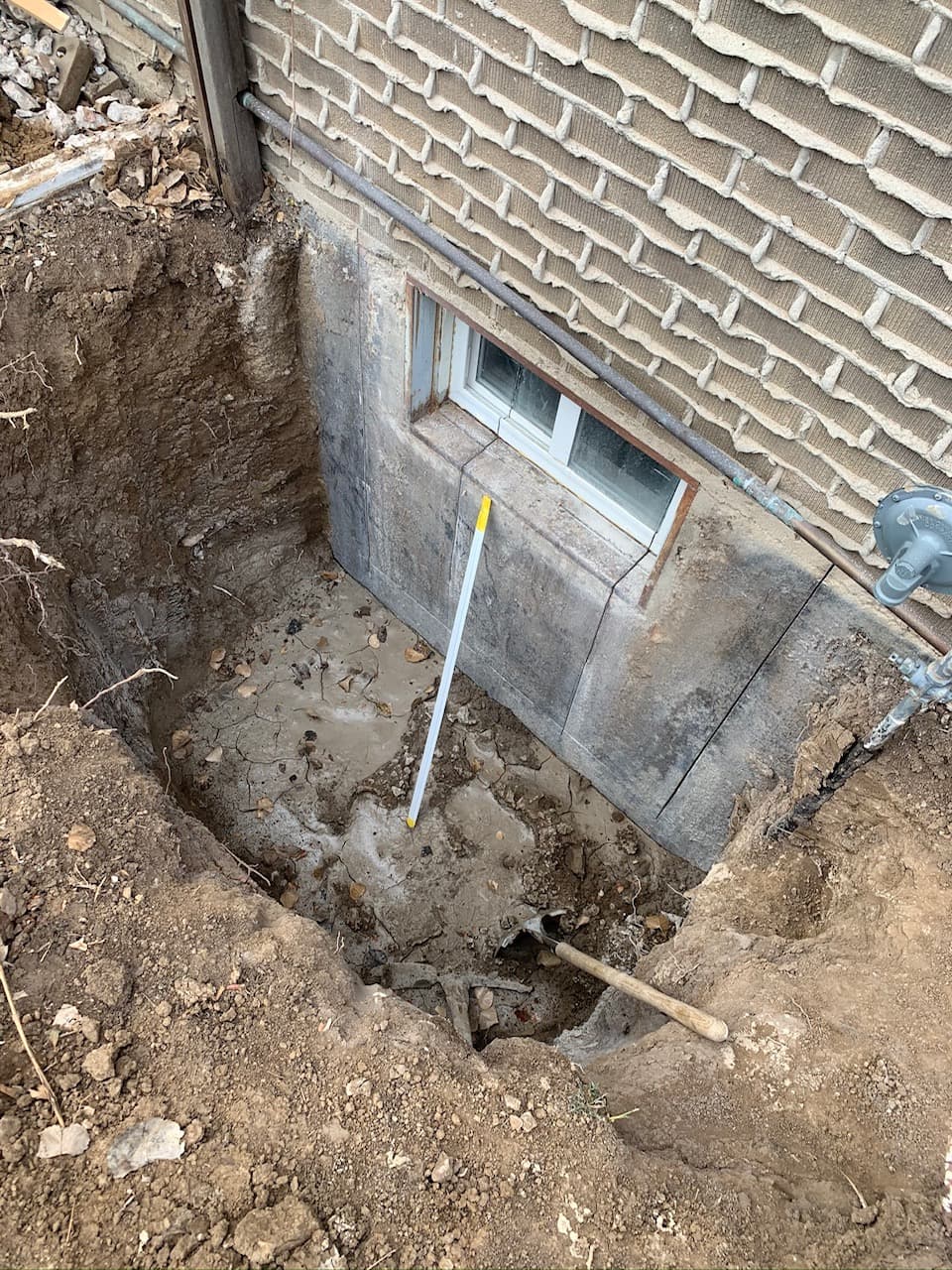 Excavation area opened near the structure for prep and access documentation.