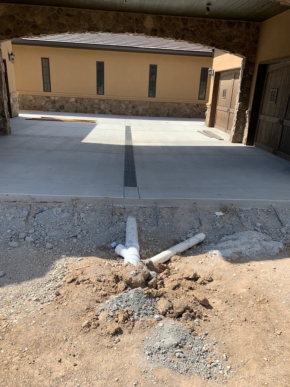 Drain line rough work captured near the garage approach before cover-up.